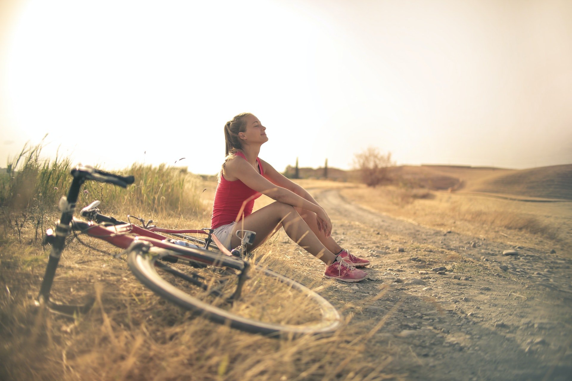 Zittende vrouw op de grond die aan het genieten in van de zon